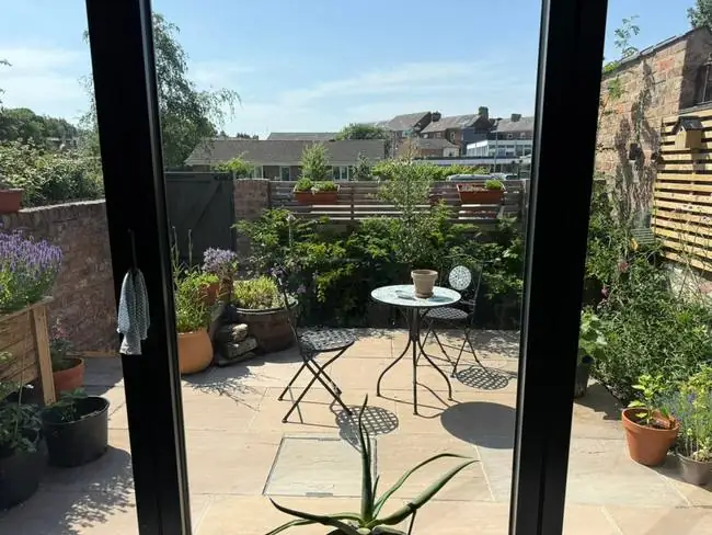 The current garden with pots, a barrel pond, two chairs and a bird box